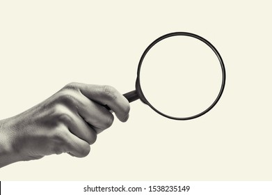 Female Hand Holding The Magnifying Glass On Isolated Background. Black And White Image.