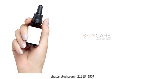 Female hand holding up a mock-up dropper bottle with empty label in a cosmetology and skincare concept with copyspace to de side for your text isolated on white with copy space