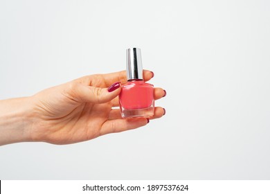 Female Hand Holding Nail Polish Against White Background