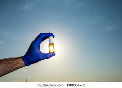 Female Hand Holding Nasal Spray On Blue Sky Background. Seasonal Allergy And Common Cold Concept.