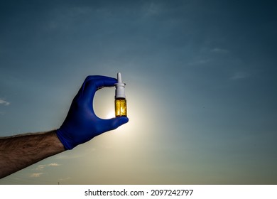 Female Hand Holding Nasal Spray On Blue Sky Background. Seasonal Allergy And Common Cold Concept.