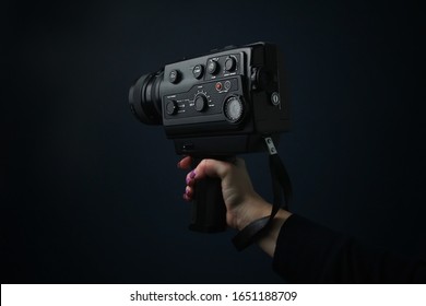 Female Hand Holding An Old Super 8 Mm Film Camera Against Dark Background