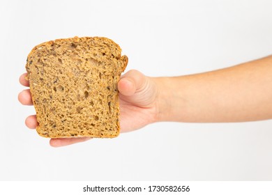 Female Hand Holding One Slice Of Cereal Loaf. Piece Of Baked At Home Bread Made Of Rye Flour Isolated On White Background. Studio Shot. Top View. Homemade Bakery And Nutrition Concept