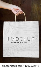 Female hand holding a paper bag mockup