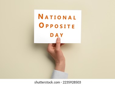 Female hand holding paper sheet with text NATIONAL OPPOSITE DAY on light background - Shutterstock ID 2235928503