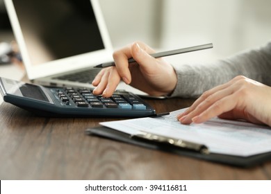 Female hand holding a pen and using calculator while filling in the individual income tax return, close up - Shutterstock ID 394116811
