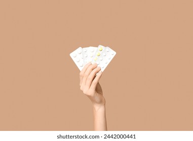 Female hand holding pills in blister packs on beige background - Powered by Shutterstock