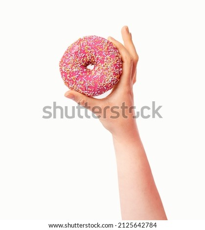 Female hand holding pink donut over white background. Top view, flat lay. Sweet, dessert, diet concept. Banner with copy space. Weight lost after holidays. 