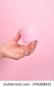 Female Hand Holding Plastic Unbranded Tube On Pink Background. Flacon For Cream, Body Lotion. Container For Cosmetics Product. Skincare And Beauty Concept. Mockup, Copy Space.conceptual Shooting.