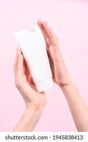 Female Hand Holding Plastic Unbranded Tube On Pink Background. Flacon For Cream, Body Lotion. Container For Cosmetics Product. Skincare And Beauty Concept. Mockup, Copy Space.conceptual Shooting.