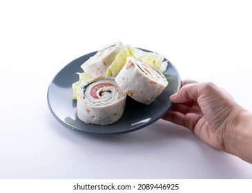 Female Hand Holding A Plate With Turkey Roll Ups With Cheese And Vegetables, Close-up Of Delicious Appetizer. Tortilla Pieces.