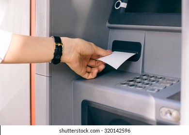 Female Hand Holding A Receipt Obtained From The ATM After Withdrawing Cash. The Outer Bank Terminal.