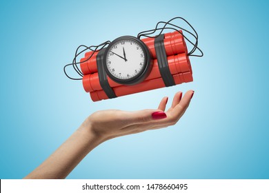 Female hand holding red dynamite stick time bomb on blue background. Digital art. Explosive materials. Time bomb ready to explosion.