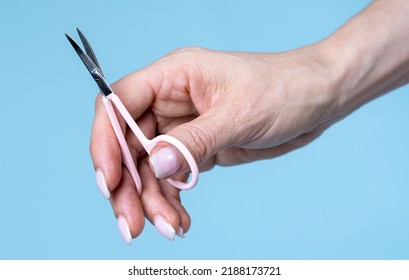 Female Hand Holding Scissors Isolated On  Blue Background