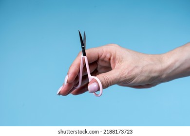 Female Hand Holding Scissors Isolated On  Blue Background