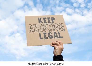 Female hand holding sign with slogan Keep Abortion Legal. Woman with placard supporting abortion rights at protest rally demonstration.