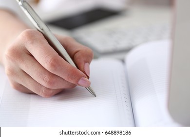 Female Hand Holding Silver Pen Ready To Make Note In Opened Notebook Sheet. Businesswoman In Suit At Workspace Make Thoughts Records At Personal Organizer, White Collar Conference, Signature Concept