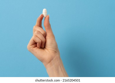 A Female Hand Holding A Single Pill On Colorfull Background