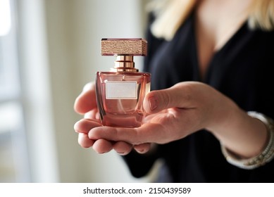Female hand holding small glass bottle with scented perfume. Grooming products for women. Self care and beauty treatment. International Women's day. The best present for women.