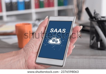 Female hand holding a smartphone with saas concept