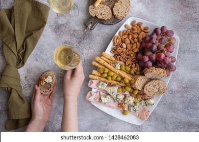 Female Hand Holding Snack And Glass Of Wine .Tasting Party Background. Top View.