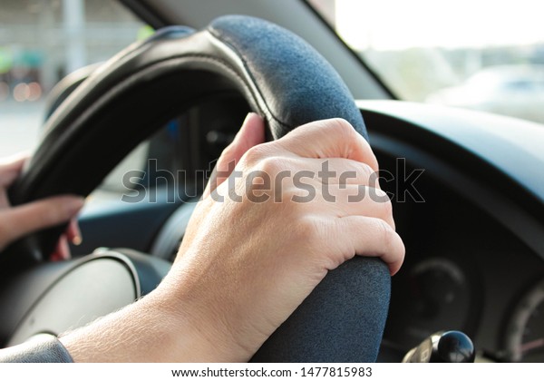 Female hand holding the steering wheel of the\
car close-up.