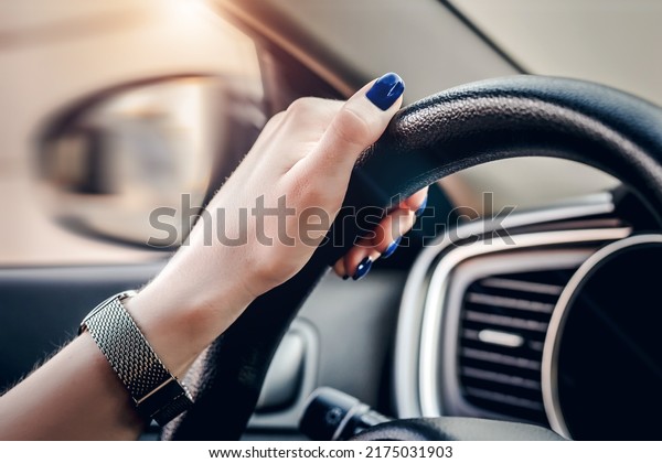 female hand is holding the steering wheel of a\
car. close up. Traveling alone. Traffic Laws. Learns to drive a\
car. woman driver