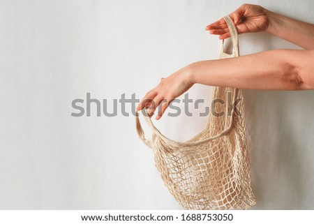 female hand holding string back against white wall copy space 