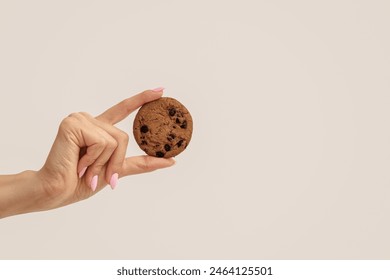 Female hand holding sweet cookie with chocolate chips on white background - Powered by Shutterstock