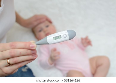 female hand holding a thermometer with high temperature on the background of a sick child - Shutterstock ID 581164126