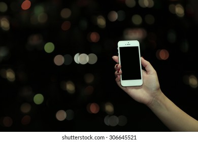 Female Hand Holding Touch Screen Mobile Phone On Blurred Night Lights Background