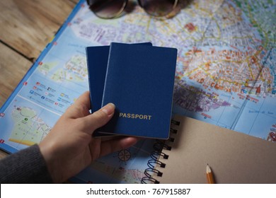 Female Hand Holding Two Passports On A Background Map. Compass, Notepad, Pencil And Book. Top View.