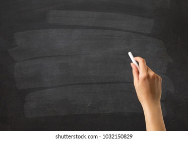 Female hand holding white chalk in front of a blank blackboard - Powered by Shutterstock