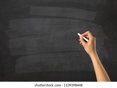 Female hand holding white chalk in front of a blank blackboard - Powered by Shutterstock