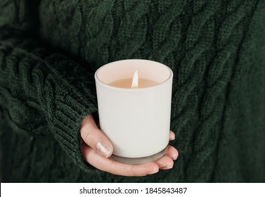 female hand holding white soy candle. teenager girl wearing green sweater and holding burning candle. holidays concept. spiritual experience and inner peace. selective focus - Powered by Shutterstock