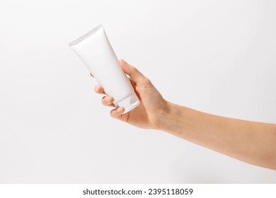 Female hand holding white tube of body or face cream mockup on white isolated background. Beauty products concept, product presentation. Image for your design and space for your text - Powered by Shutterstock