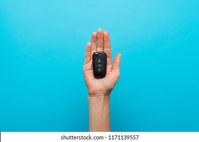 Female Hand Holds A Car Key In The Palm On A Blue Background. Co