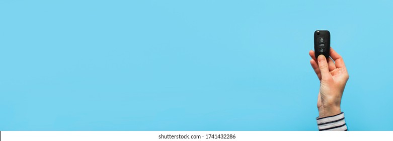 Female hand holds car keys on a blue background. Concept car, car rental, gift, driving lessons, driving license. Banner. Flat lay, top view - Powered by Shutterstock