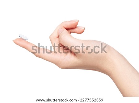 Female hand holds contact lense on finger.