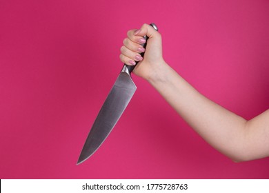 Female Hand Holds Down A Knife On A Pink/red Background