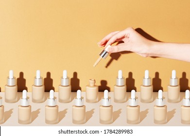 A Female Hand Holds A Dropper For Applying Bb Foundation Cream. Opened And Closed Jars Of A Cosmetic Makeup Product On A Beige Background. Pattern Of Beauty Products Packaging