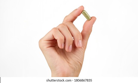female hand holds in fingers capsule superfoods moringa or spirulina 