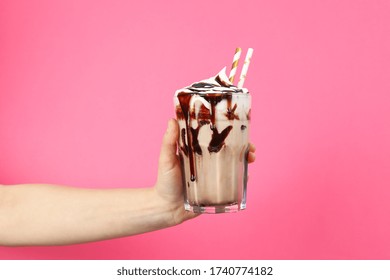 Female hand holds glass of chocolate milkshake on pink background - Powered by Shutterstock