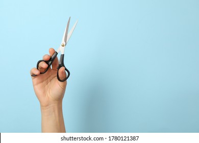 Female hand holds hairdresser scissors on blue background