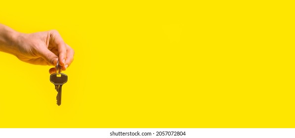 Female Hand Holds House Keys On A Yellow Background.Flat Lay, Banner