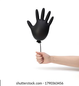 A Female Hand Holds An Inflated Black Surgical Glove On A White Background. Prevention Of Coronavirus, Covid-19. Minimal Healthcare Concept. The Glove Looks Like A Balloon.