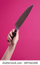 Female Hand Holds Up A Knife On A Pink Background