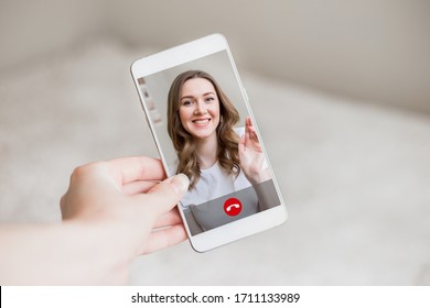 A Female Hand Holds A Mobile Phone With A Girl On The Screen, Video Chat. A Woman Makes A Video Call To Her Friend. Happy Young Girl Smiles On A Phone Screen, Interface, Call Buttons