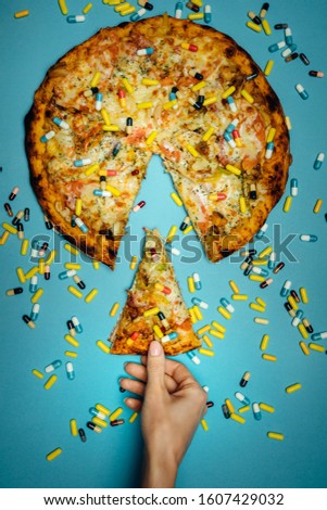 Female Hand Holds In Hand A Piece Of Pizza Sprinkled With Pills, Top view Idea. Biohacking Healthy Food Concept
