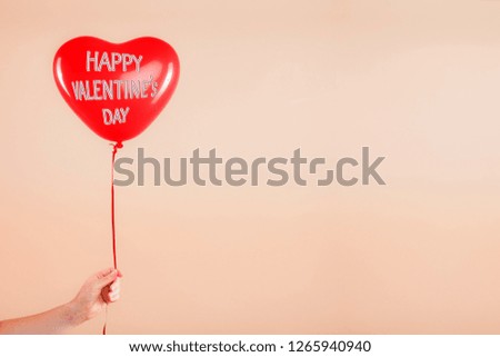 Female hand holds red rubber inflatable heart shape balloon. Love, relationship, valentines day and birthday celebration concept. Studio shot on an abstract blurred background with blank copy space